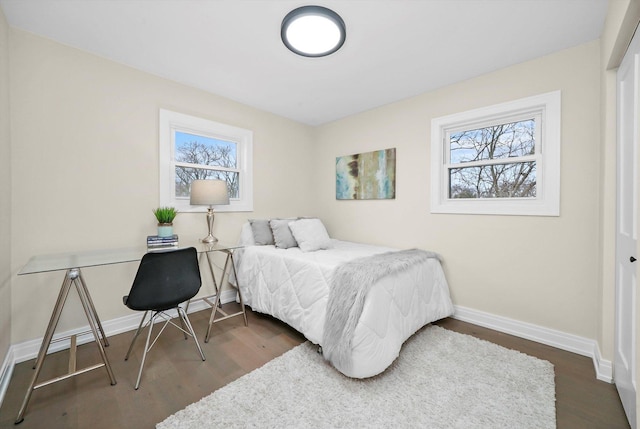 bedroom featuring multiple windows, baseboards, and wood finished floors