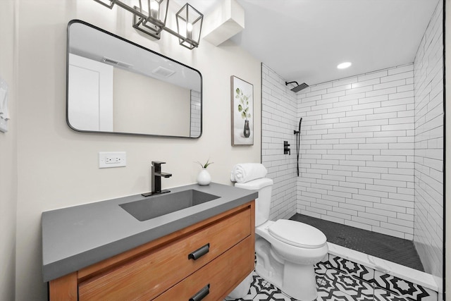 bathroom featuring toilet, tiled shower, visible vents, and vanity