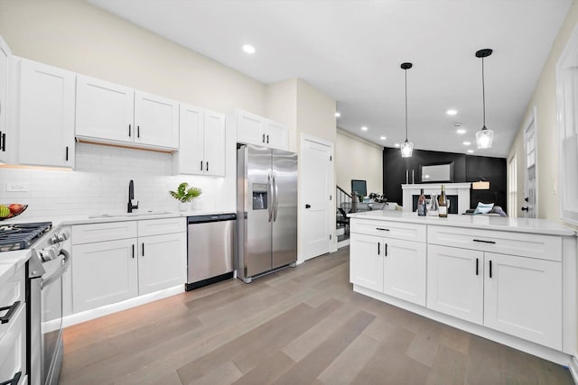 kitchen featuring decorative backsplash, white cabinets, appliances with stainless steel finishes, light wood-style floors, and a sink