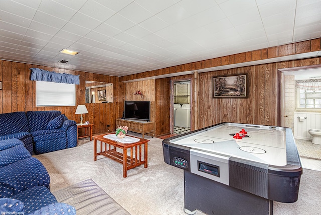 carpeted living room with washer / clothes dryer, visible vents, and wooden walls