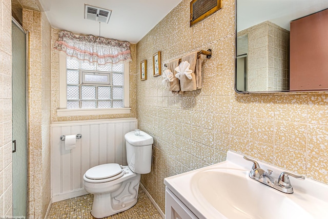 full bathroom with visible vents, wainscoting, toilet, a shower with shower door, and vanity