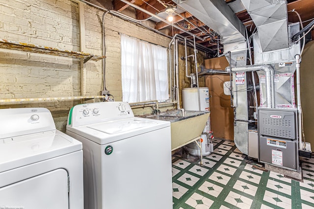 laundry room with gas water heater, brick wall, laundry area, independent washer and dryer, and tile patterned floors