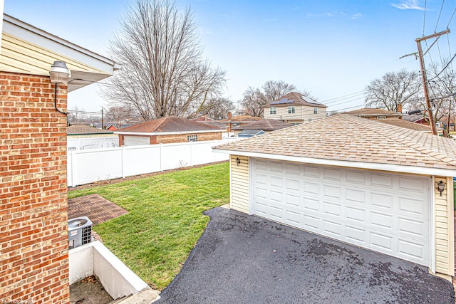 view of yard with a garage, fence, and an outbuilding