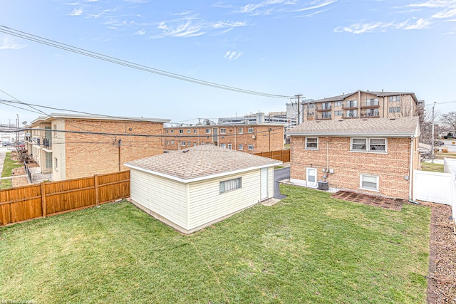 back of property with a fenced backyard, a yard, and brick siding