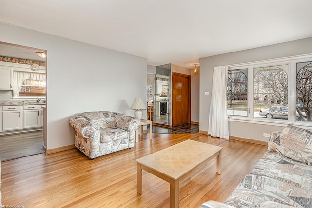 living area with visible vents, light wood-style flooring, and baseboards