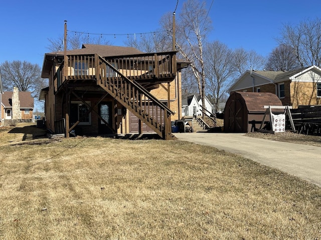 exterior space featuring a lawn, stairway, a storage shed, a deck, and an outdoor structure