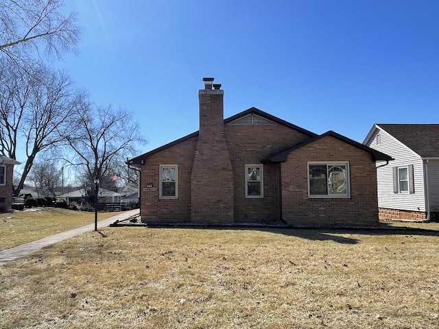 exterior space with a yard, brick siding, and a chimney