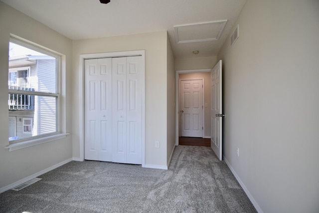 unfurnished bedroom featuring visible vents, attic access, baseboards, and carpet floors