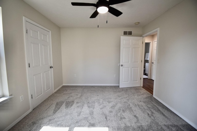 unfurnished bedroom featuring a ceiling fan, carpet, visible vents, and baseboards