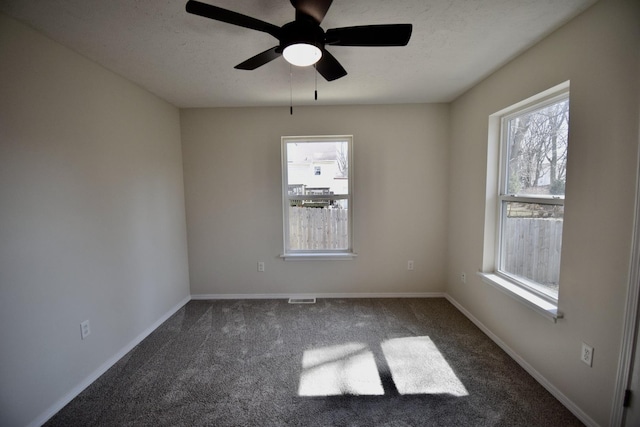 spare room with visible vents, ceiling fan, baseboards, a textured ceiling, and dark colored carpet