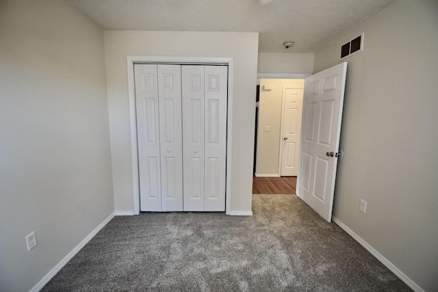 unfurnished bedroom with a closet, visible vents, carpet flooring, and baseboards