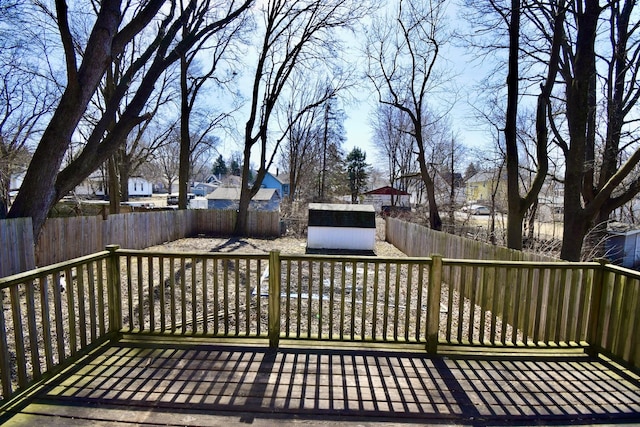 wooden deck with a fenced backyard, a residential view, a storage unit, and an outdoor structure