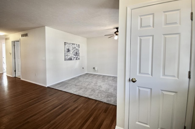 spare room with visible vents, a textured ceiling, dark wood-type flooring, and a ceiling fan