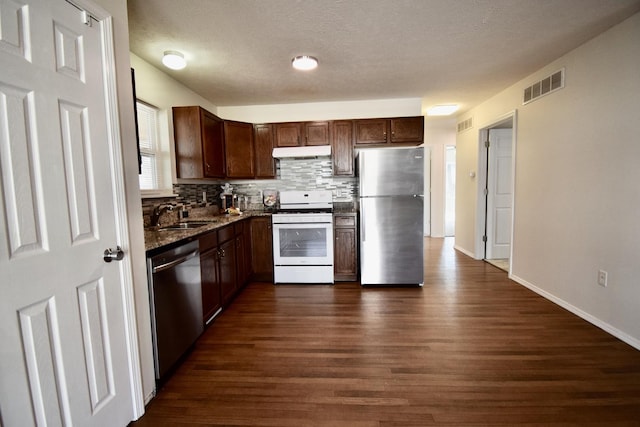 kitchen with tasteful backsplash, visible vents, under cabinet range hood, appliances with stainless steel finishes, and a sink