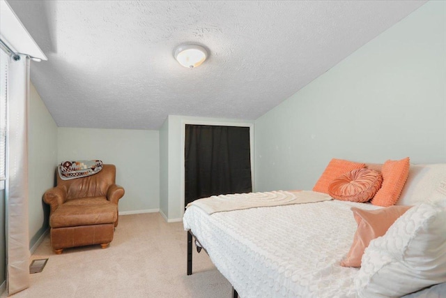 carpeted bedroom featuring vaulted ceiling, baseboards, visible vents, and a textured ceiling