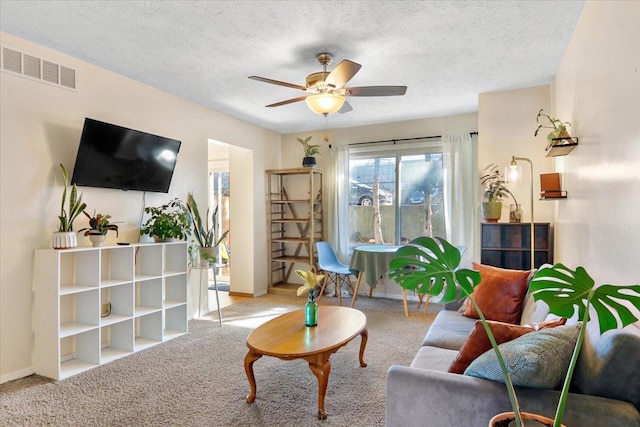 carpeted living area featuring baseboards, visible vents, a textured ceiling, and a ceiling fan