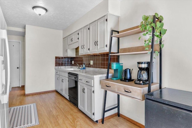 kitchen featuring open shelves, a sink, decorative backsplash, light wood-style floors, and dishwasher