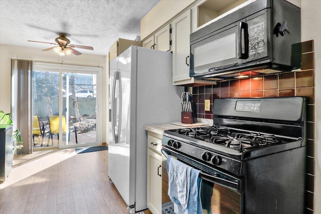 kitchen featuring black appliances, light countertops, decorative backsplash, light wood-style floors, and a textured ceiling