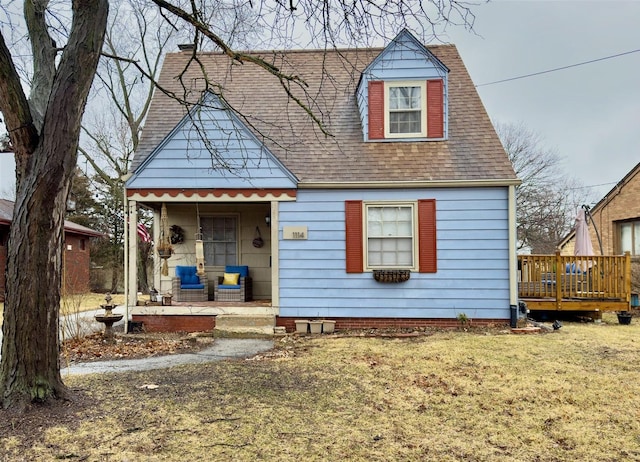 view of front facade featuring a shingled roof, outdoor lounge area, a front yard, a wooden deck, and a patio area