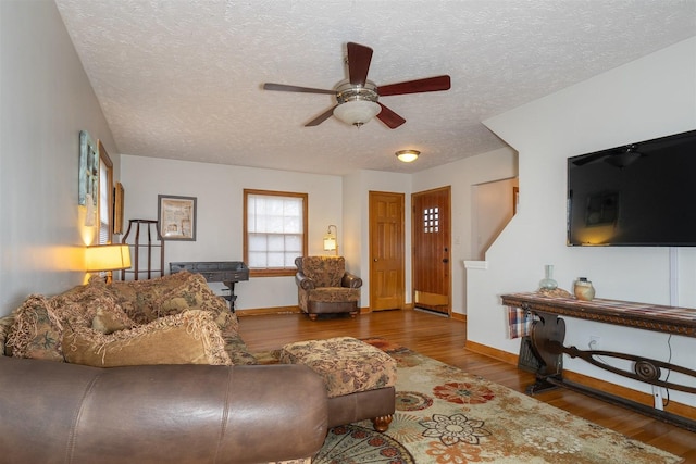 living area featuring a textured ceiling, baseboards, and wood finished floors