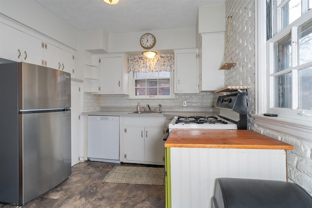 kitchen featuring white appliances, butcher block counters, a sink, white cabinetry, and backsplash