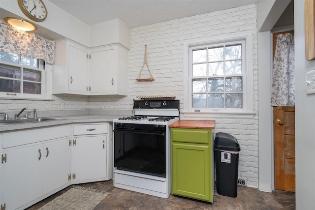 kitchen featuring a wealth of natural light, brick wall, range with gas stovetop, and a sink