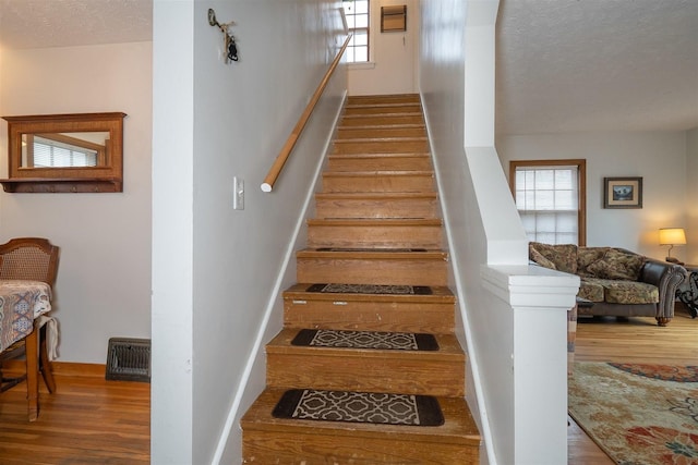 staircase with visible vents, plenty of natural light, and wood finished floors