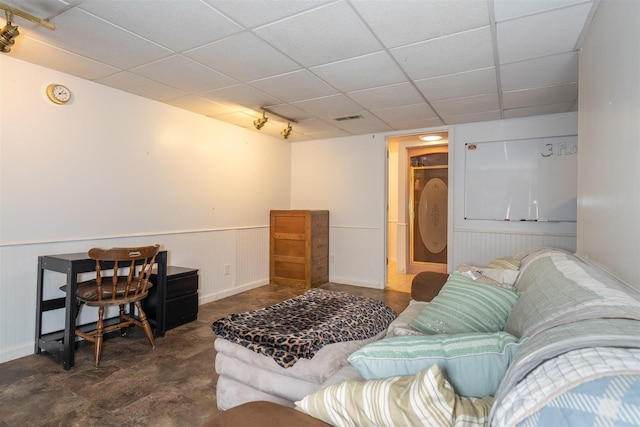 living area with visible vents, a wainscoted wall, and a paneled ceiling