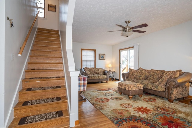 stairs featuring a textured ceiling, wood finished floors, and a ceiling fan