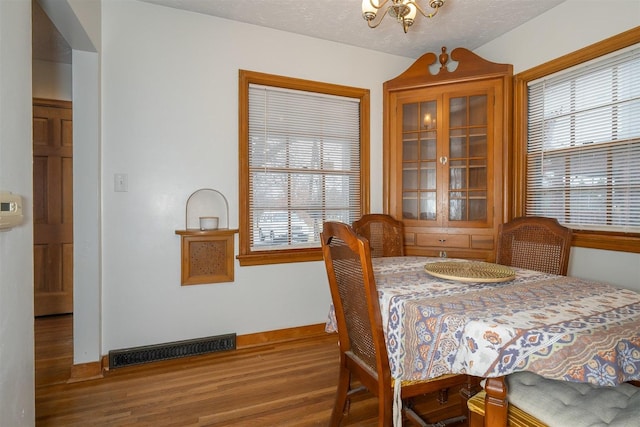 dining area with a healthy amount of sunlight, visible vents, a textured ceiling, and wood finished floors