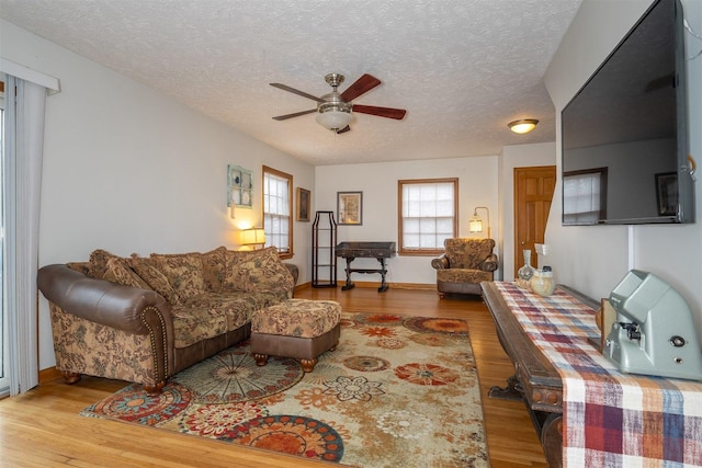 living room featuring a ceiling fan, a textured ceiling, and wood finished floors