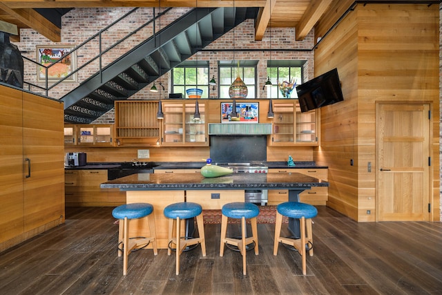 kitchen featuring wooden walls, high vaulted ceiling, a breakfast bar area, and beamed ceiling