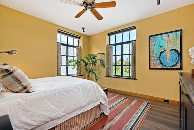 bedroom featuring a ceiling fan, baseboards, and wood finished floors