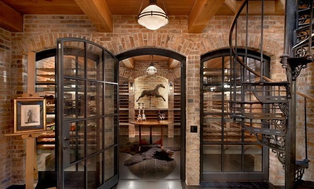 wine cellar featuring wood ceiling, beam ceiling, and brick wall