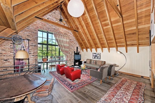 living area with wooden ceiling, wood finished floors, beamed ceiling, a wood stove, and high vaulted ceiling