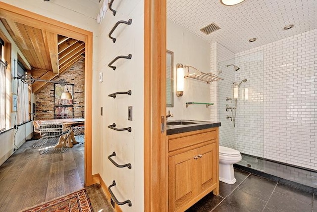 full bathroom featuring lofted ceiling, toilet, visible vents, vanity, and tiled shower