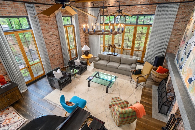 living area featuring a chandelier, french doors, a towering ceiling, and brick wall