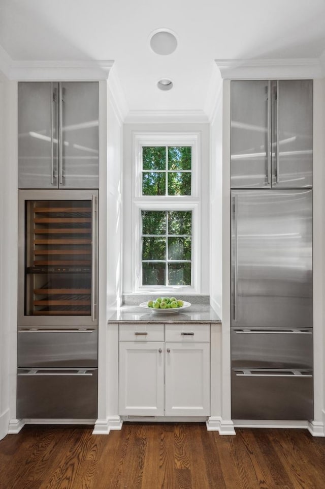 bar with dark wood finished floors, crown molding, wine cooler, and a warming drawer