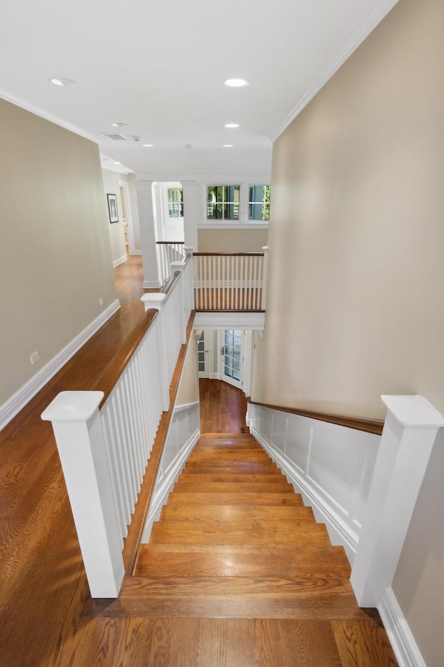 stairway featuring recessed lighting, wood finished floors, baseboards, and ornamental molding