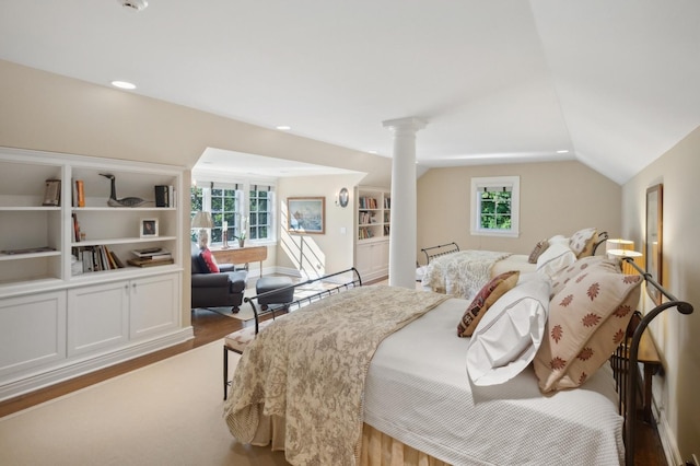 bedroom with vaulted ceiling, recessed lighting, wood finished floors, and ornate columns