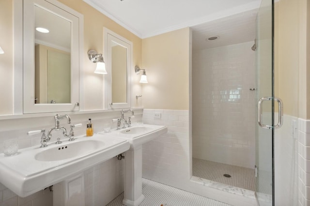 bathroom featuring tile patterned flooring, a shower stall, crown molding, wainscoting, and tile walls