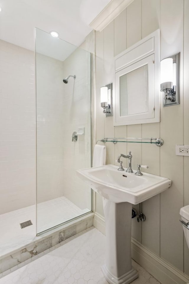 full bathroom with toilet, tiled shower, and a sink