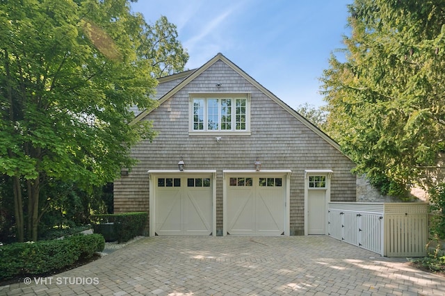 view of property exterior featuring an attached garage and a gate