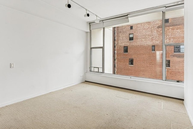 carpeted spare room with baseboards and rail lighting