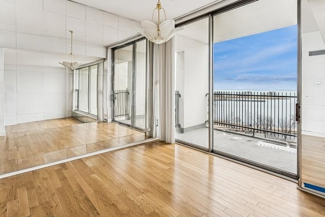 empty room with wood finished floors, visible vents, and expansive windows