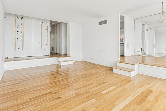 unfurnished living room featuring visible vents and wood finished floors