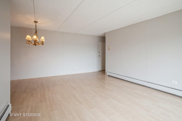 spare room featuring a baseboard heating unit, light wood-type flooring, and a chandelier