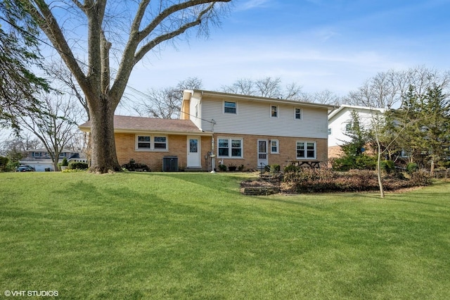 rear view of house featuring a yard, central AC unit, and brick siding