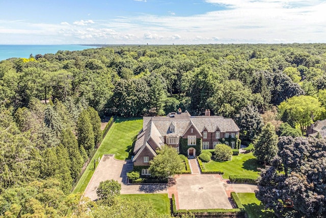 birds eye view of property featuring a water view and a wooded view