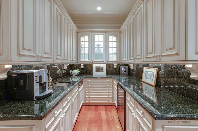 kitchen with light wood-style flooring, a sink, decorative backsplash, dark stone countertops, and crown molding